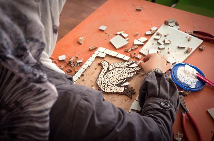 Za’atari refugee camp in Jordan, 2015. A woman's hand crafts a mosaic depicting a peace dove.  UN Women provides economic empowerment and protection programming for women and girls in the camp. Photo: UN Women/Christopher Herwig